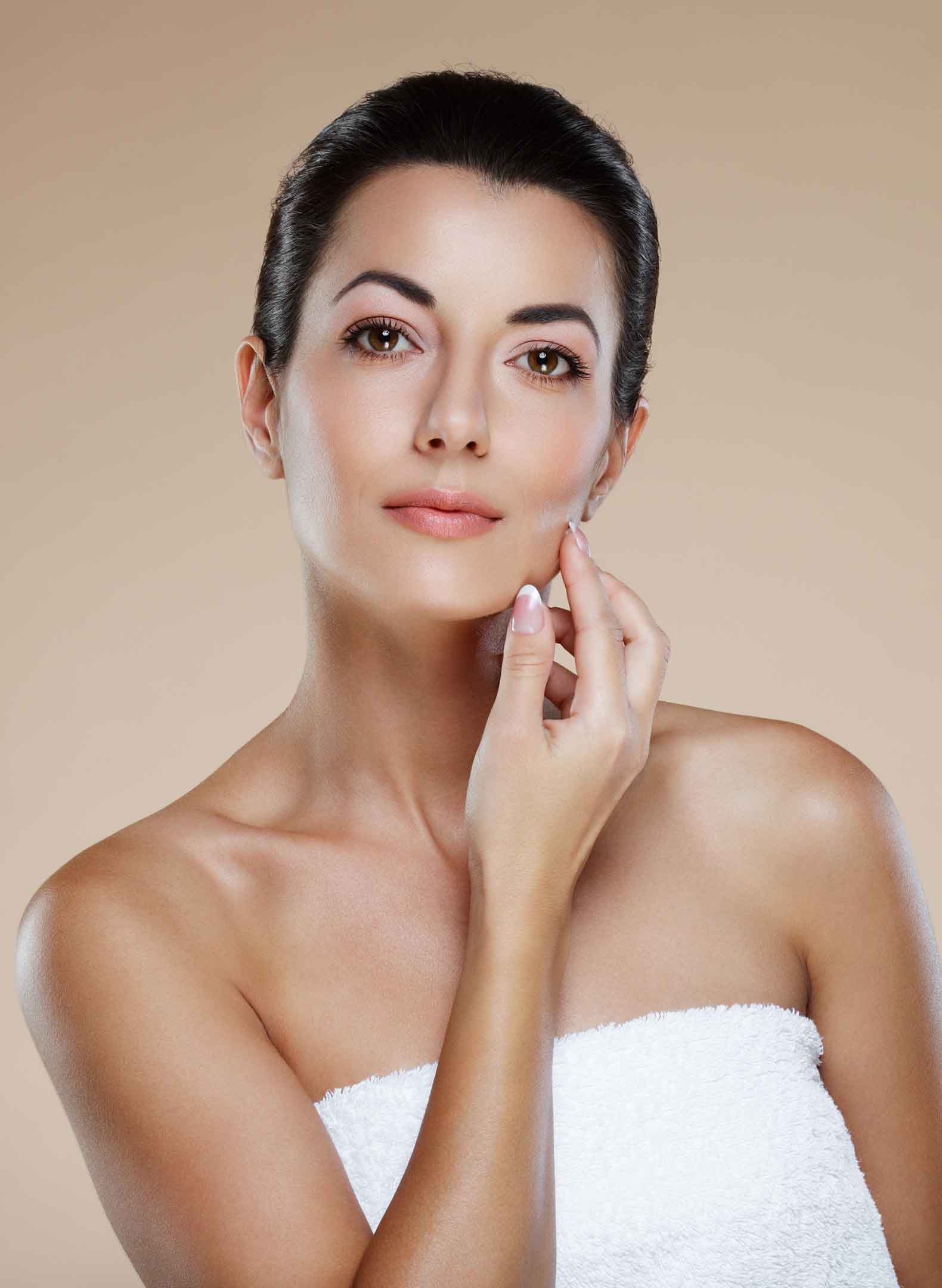 Woman wearing a towel touching her face