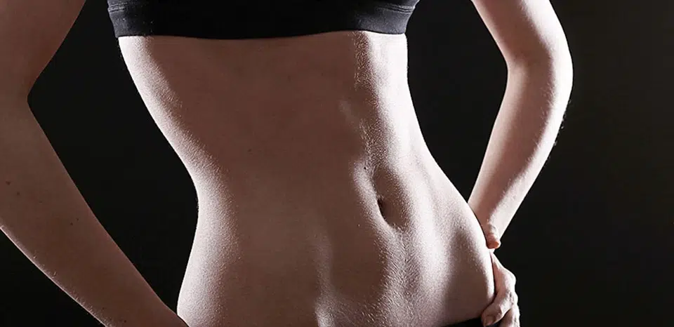 Woman's toned abs against a black background